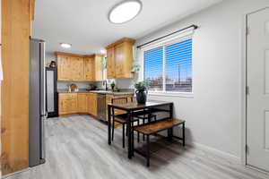 Kitchen with light wood finish cabinetry, stainless steel appliances, light wood-style flooring, and light countertops