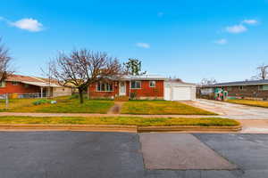 Ranch-style house with concrete driveway, brick siding, and roof mounted solar panels