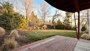 Fenced backyard with a patio, a storage shed, and view of wooded area