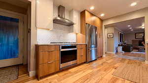 Dual tone kitchen featuring modern cabinets, stainless steel appliances, light wood finished floors, light countertops, and recessed lighting