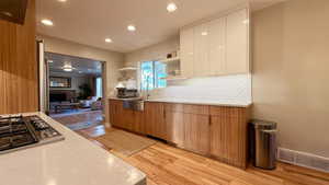 Dual tone kitchen featuring open shelves, light wood-style flooring, two tone cabinetry, modern cabinets, and recessed lighting