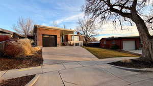 Ranch-style home featuring a garage, brick siding, and concrete driveway