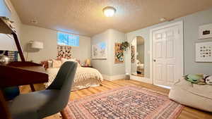 Bedroom featuring light wood-style floors, a textured ceiling, and arched walkways