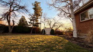 Yard at dusk featuring a fenced backyard and a storage shed