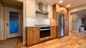 Kitchen featuring stainless steel appliances, modern cabinets, light wood-style flooring, recessed lighting, and ornamental molding