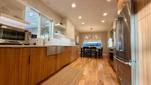 Dual tone kitchen featuring stainless steel appliances, open shelves, light wood finished floors, modern cabinets, and decorative backsplash