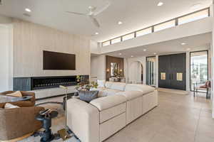 Living area featuring ceiling fan, arched walkways, recessed lighting, a high ceiling, and light tile patterned floors