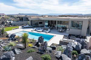 Back of property with stucco siding, an outdoor pool, a fire pit, and a mountain view