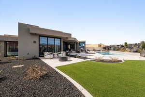 Back of house featuring a patio area, stucco siding, a yard, and an outdoor living space