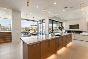 Kitchen with open floor plan, a large island, modern cabinets, wood finish cabinetry, and expansive windows