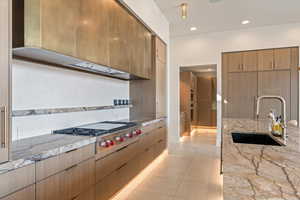 Kitchen featuring modern cabinets, light stone countertops, stainless steel gas stovetop, recessed lighting, and light tile patterned floors