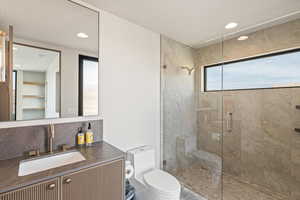 Bathroom featuring a shower stall, vanity, backsplash, and recessed lighting