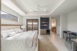 Bedroom with a raised ceiling, beverage cooler, bar with sink, recessed lighting, and ceiling fan