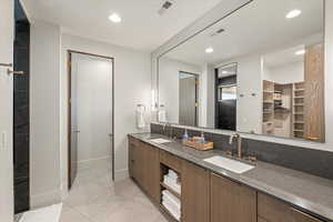 Full bathroom with double vanity, a walk in closet, light tile patterned floors, and recessed lighting