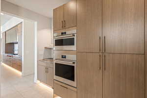 Kitchen with stainless steel appliances, modern cabinets, light tile patterned floors, and light wood finish cabinets