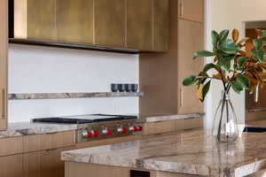 Kitchen with modern cabinets, light countertops, extractor fan, and stainless steel gas stovetop