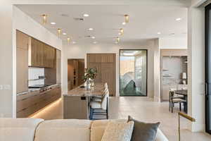 Kitchen featuring a breakfast bar area, a center island with sink, tasteful backsplash, recessed lighting, and stainless steel gas cooktop