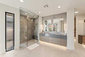 Bathroom with double vanity, a walk in closet, a shower stall, recessed lighting, and light tile patterned floors