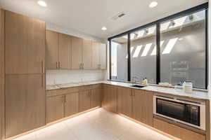 Kitchen featuring light stone countertops, stainless steel microwave, and recessed lighting