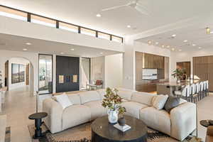 Living room with recessed lighting, arched walkways, light tile patterned floors, and a ceiling fan
