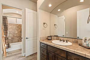 Bathroom with vanity, recessed lighting, shower / bath combo with shower curtain, and light wood-style flooring