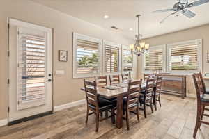 Dining space featuring wood finished floors, a chandelier, a ceiling fan, and healthy amount of natural light