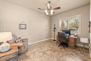 Office area featuring a ceiling fan and stone finish flooring