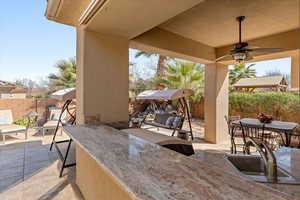 Fenced backyard featuring a patio area, an outdoor bar and dining area, and ceiling fan
