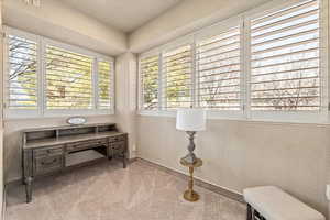 Office space with light carpet and a textured wall