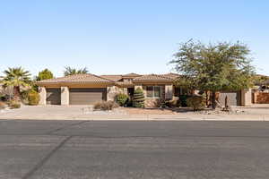 View of front facade with an attached garage, a tiled roof, driveway, stucco siding, and stone siding