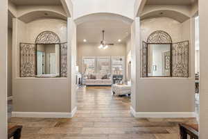 Hall featuring light wood finished floors, arched walkways, and recessed lighting