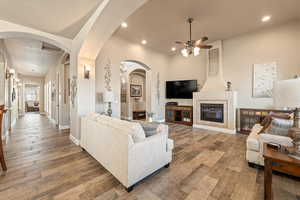 Living area with arched walkways, hardwood / wood-style flooring, a fireplace, ceiling fan, and recessed lighting