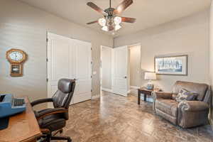 Office featuring a ceiling fan and light stone finish floors