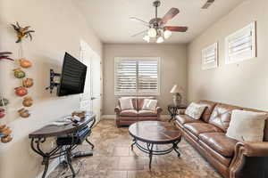 Living area with ceiling fan and baseboards