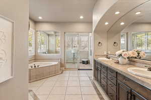 Bathroom featuring double vanity, plenty of natural light, a garden tub, recessed lighting, and inlaid floor details