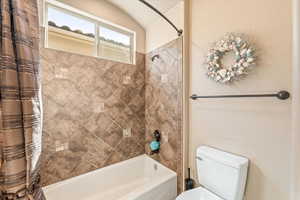 Bathroom featuring toilet and shower / tub combo with curtain