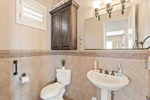 Half bathroom with wainscoting and tile walls