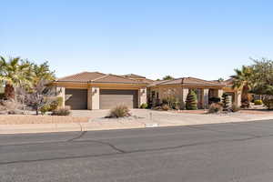 View of front of home with an attached garage, stucco siding, concrete driveway, and a tile roof