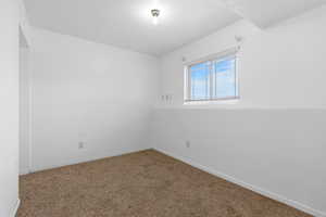 Carpeted spare room featuring baseboards