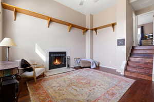 Living area featuring dark wood-style floors, a fireplace, and ceiling fan
