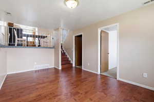 Unfurnished living room featuring dark wood-type flooring and a textured ceiling
