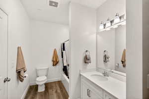 Bathroom with vanity, dark wood-style flooring, and shower / bathtub combination with curtain