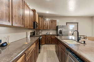 Kitchen featuring stainless steel appliances, dark stone counters, light wood-style flooring, recessed lighting, and wood finish cabinetry