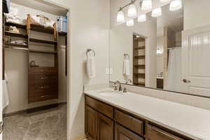Full bathroom featuring vanity, a shower with shower curtain, light colored carpet, and a spacious closet