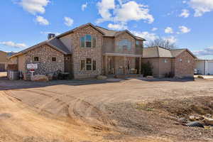 View of front of property featuring stone siding, a balcony, and a chimney