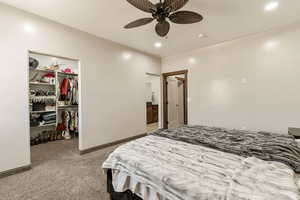 Bedroom featuring light carpet, a walk in closet, a ceiling fan, and recessed lighting
