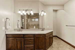 Full bath featuring double vanity, light tile patterned floors, and a shower