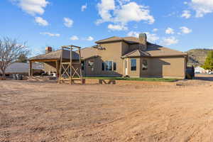Rear view of property featuring a chimney, a patio, and stucco siding