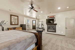 Bedroom with light colored carpet, recessed lighting, access to outside, ceiling fan, and a glass covered fireplace