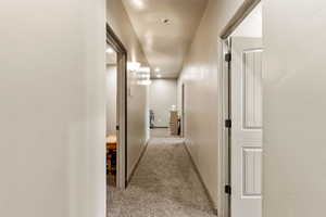Hall featuring light carpet and baseboards
